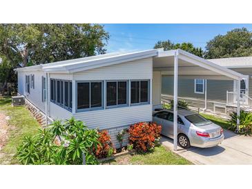 Well-maintained home featuring a carport, screened-in porch, and colorful landscaping at 9790 66Th N St # 353, Pinellas Park, FL 33782