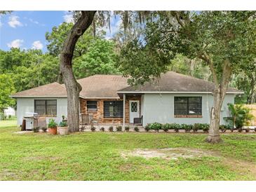 Charming single-story home featuring a brick facade, covered porch, mature landscaping, and a well-manicured lawn at 11317 Fort King Rd, Dade City, FL 33525