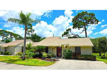 Charming single-story home with a well-manicured lawn and lush landscaping, including a tall palm tree at 13 Windrush Bay Dr, Tarpon Springs, FL 34689