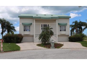 Stylish two-story home featuring a green roof, twin garages, and mature palm trees at 3402 Amberjack Dr, Hernando Beach, FL 34607