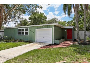 Charming single-story home with an attached garage, green exterior, and a red front door at 607 E River Dr, Temple Terrace, FL 33617