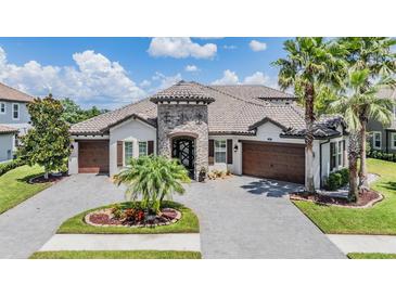 Beautiful Mediterranean style home with tile roof, stone accents, and three-car garage at 7162 Graybrook Dr, Wesley Chapel, FL 33545