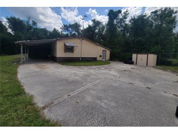 Cozy home featuring a convenient carport and expansive driveway, nestled near lush greenery and a storage shed at 9910 Jerome Dr, New Port Richey, FL 34654