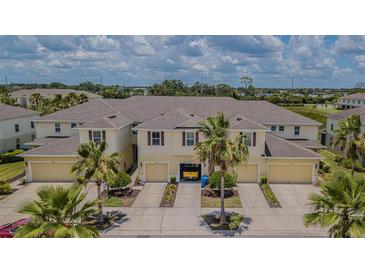 Inviting townhome exterior showcasing charming architecture, individual garages, and tropical landscaping under a partly cloudy sky at 10830 Verawood Dr, Riverview, FL 33579