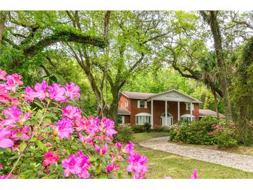 Beautiful two-story brick home with a circular driveway surrounded by lush azalea bushes and a manicured lawn at 11159 Cindy Dr, Brooksville, FL 34601
