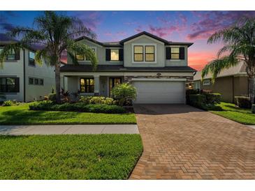 Beautiful two-story home featuring lush landscaping, brick driveway, and a welcoming facade at sunset at 19209 Long Lake Ranch Blvd, Lutz, FL 33558