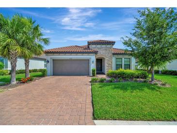 Charming home featuring a terracotta tile roof, brick paved drive, and a two-car garage at 5320 Morey Farms Loop, Palmetto, FL 34221