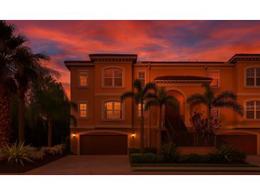 Elegant townhouse featuring a two-car garage, complemented by lush landscaping and a stunning sunset backdrop at 6513 Sand Shore Ln, New Port Richey, FL 34652