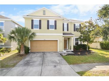 Inviting two-story home featuring a well-manicured lawn, attached garage, and neutral-toned exterior at 11539 Tangle Branch Ln, Gibsonton, FL 33534