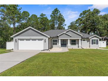 Charming single-story home with a manicured lawn, gray siding, and an attached two-car garage at 12333 Harris Hawk Rd, Weeki Wachee, FL 34614