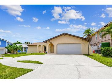 Charming single-story home featuring a well-manicured lawn, neutral paint, and a spacious driveway with palm tree at 12476 81St Ct, Seminole, FL 33772