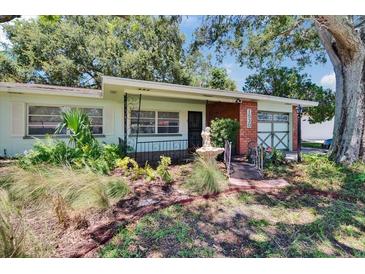 Charming home featuring lush landscaping, quaint fountain, and a delightful bridge walkway at 1530 Erin Ln, Clearwater, FL 33755