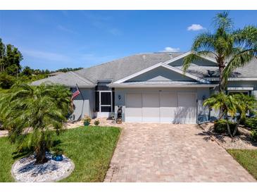 Charming single-story home with a brick driveway, an attached two-car garage, and beautiful tropical landscaping at 717 Manchester Woods Dr # 717, Sun City Center, FL 33573