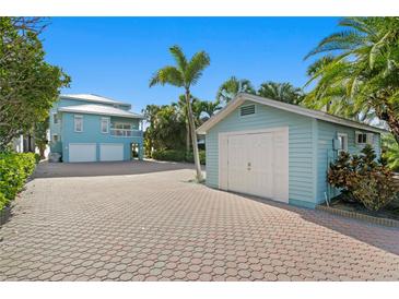 Charming blue house with a two-car garage and an additional single-car garage, surrounded by lush greenery at 20060 Gulf Blvd, Indian Shores, FL 33785