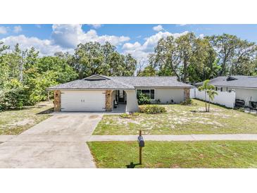 Charming single-story home with stone accents, mature trees, and a well-manicured front yard at 1403 Tallahassee Dr, Tarpon Springs, FL 34689