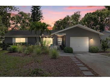 Charming single-story home with lush landscaping, a garage, and a welcoming entrance at dusk at 2850 Doone Cir, Palm Harbor, FL 34684