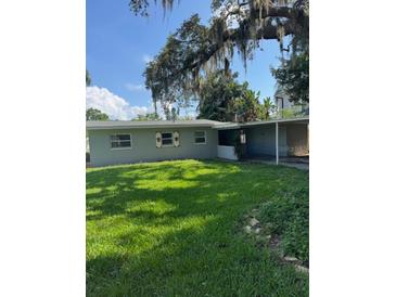 Charming single-story home featuring a well-maintained lawn and covered carport, shaded by mature trees at 3111 S Canal Dr, Palm Harbor, FL 34684
