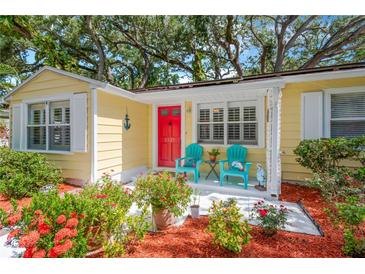 Charming home featuring a vibrant red door, colorful chairs, and lush landscaping for a welcoming entrance at 3129 W Villa Rosa St, Tampa, FL 33611
