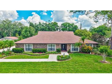 Charming brick home with well-manicured lawn, trimmed shrubs, and beautiful landscaping at 3923 Hudson Ln, Tampa, FL 33618