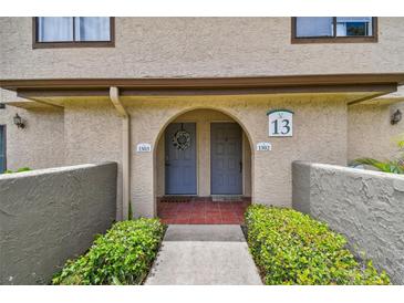 Charming condo entrance featuring a welcoming archway, gray doors, and lush green landscaping at 6262 142Nd N Ave # 1302, Clearwater, FL 33760