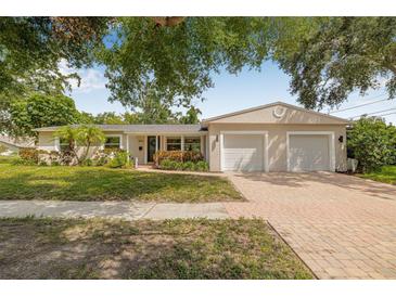 Charming single-story home with lush landscaping, brick driveway, and a two-car garage at 8010 Par N Ave, St Petersburg, FL 33710