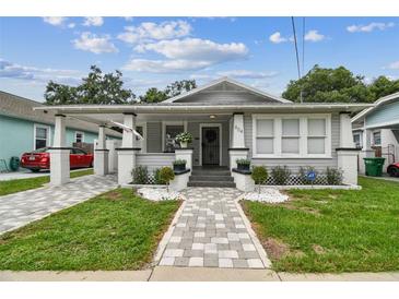 Charming home featuring a quaint front porch, freshly painted exterior, and beautifully manicured landscaping at 904 E Hamilton Ave, Tampa, FL 33604