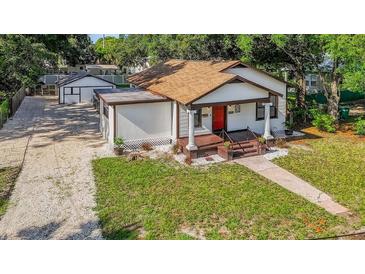 Charming bungalow with a red front door, gravel driveway and detached garage at 1217 E 29Th Ave, Tampa, FL 33605