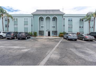 Three story condo building with light blue painted facade, arched entry and ample parking at 1706 Belleair Forest Dr # 146, Belleair, FL 33756