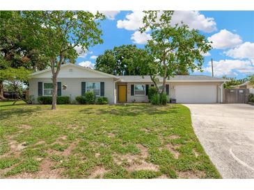 Charming home featuring a well-manicured front lawn, mature trees, and an inviting yellow front door at 2325 W Knollwood Pl, Tampa, FL 33604
