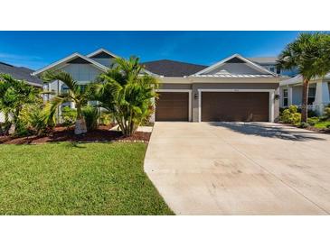Charming home featuring a two-car garage, well-manicured lawn, and tropical landscaping at 4906 Los Robles Ct, Palmetto, FL 34221