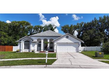 Charming single-story home with a well-manicured lawn, a two-car garage, and lovely curb appeal at 6318 Ashfield Pl, Wesley Chapel, FL 33545