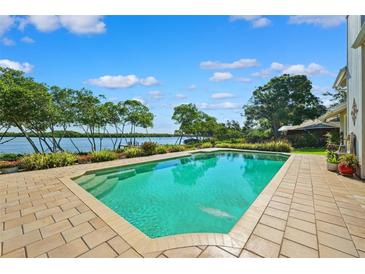Beautiful waterfront pool with brick trim and lush landscaping under a sunny sky at 1531 75Th Ne Cir, St Petersburg, FL 33702