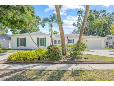 Charming white brick home with green shutters, palm trees, and lush landscaping creates inviting curb appeal at 2320 Harn Blvd, Clearwater, FL 33764