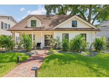 Charming home boasts a lush green lawn and brick pathway leading to a welcoming front porch with unique architectural details at 2512 W Jetton Ave, Tampa, FL 33629