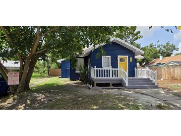 Charming blue home featuring a bright yellow door and a cozy front porch at 305 E Adalee St, Tampa, FL 33603