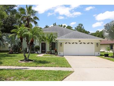 Charming single-story home with a two-car garage, landscaped yard and beautiful palm trees at 4948 Ridgemoor Cir, Palm Harbor, FL 34685