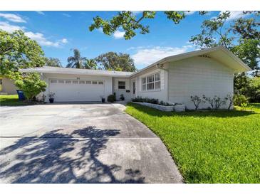 Charming single-story home featuring a well-manicured lawn and a two-car garage on a sunny day at 917 Pineview Ave, Clearwater, FL 33756