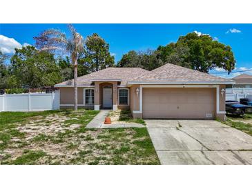 Single story home with neutral paint, arched windows, 2-car garage, and palm tree in the front yard at 13337 Tubeck St, Spring Hill, FL 34609