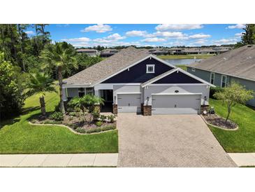 Beautiful one story home with a manicured lawn, lush landscaping, and a brick paver driveway at 1846 Moorhen Way, Lutz, FL 33558