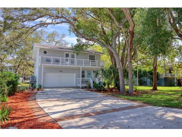 Charming two-story home with a large driveway, balcony, and mature trees at 408 Georgia Ave, Crystal Beach, FL 34681