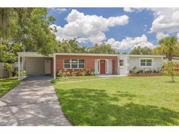 Charming single-story home with red brick accents, a spacious lawn, and mature landscaping at 505 Broxburn Ave, Temple Terrace, FL 33617