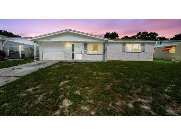 Charming single-story home featuring a well-maintained lawn and attached garage with a beautiful sunset sky at 10831 Manchester Rd, Port Richey, FL 34668