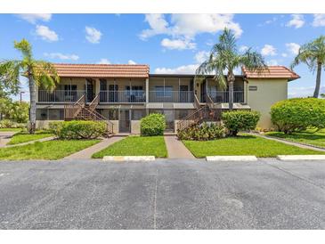 Condominium exterior with palm trees, green grass and landscaping at 2420 Winding Creek Blvd # 209, Clearwater, FL 33761
