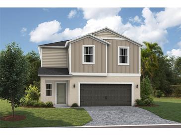 Charming two-story home featuring neutral siding, a paved driveway, manicured lawn, and attached two-car garage at 36972 Sagemoor Dr, Zephyrhills, FL 33541