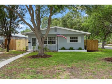 Charming home featuring a manicured lawn and a quaint front porch, enhanced by mature trees and an American flag at 501 74Th N Ave, St Petersburg, FL 33702