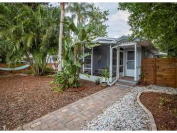 Charming single-story home featuring a screened-in porch and lush landscaping with a brick pathway to the front door at 5521 Dartmouth N Ave, St Petersburg, FL 33710