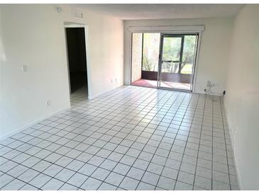 Bright living room featuring tile floors, neutral walls, and sliding glass doors to a screened lanai at 6342 Newtown Cir # A4, Tampa, FL 33615