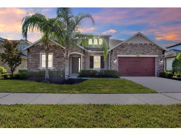 Beautiful single-story home featuring stone accents, a manicured lawn, and a two-car garage at 2120 Gwynhurst Blvd, Wesley Chapel, FL 33543