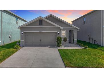 Charming home featuring a gray exterior, well-manicured lawn, and a two-car garage, enhanced by landscaping at 34033 Jasper Stone Dr, Wesley Chapel, FL 33543