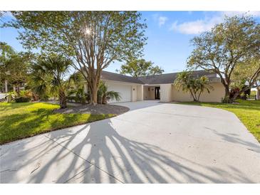 Charming single-story home featuring a circular driveway, mature trees, and a well-manicured lawn at 4157 Marine Pkwy, New Port Richey, FL 34652